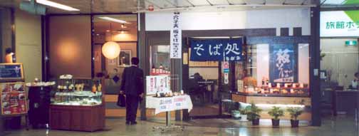 A photo of a
 Salaryman about to decide to enter the more upscale of two small restaurants
 side by side, with the usual displays, in the main train station in Sendai,
 Japan, an image in which no faces are quite visible.